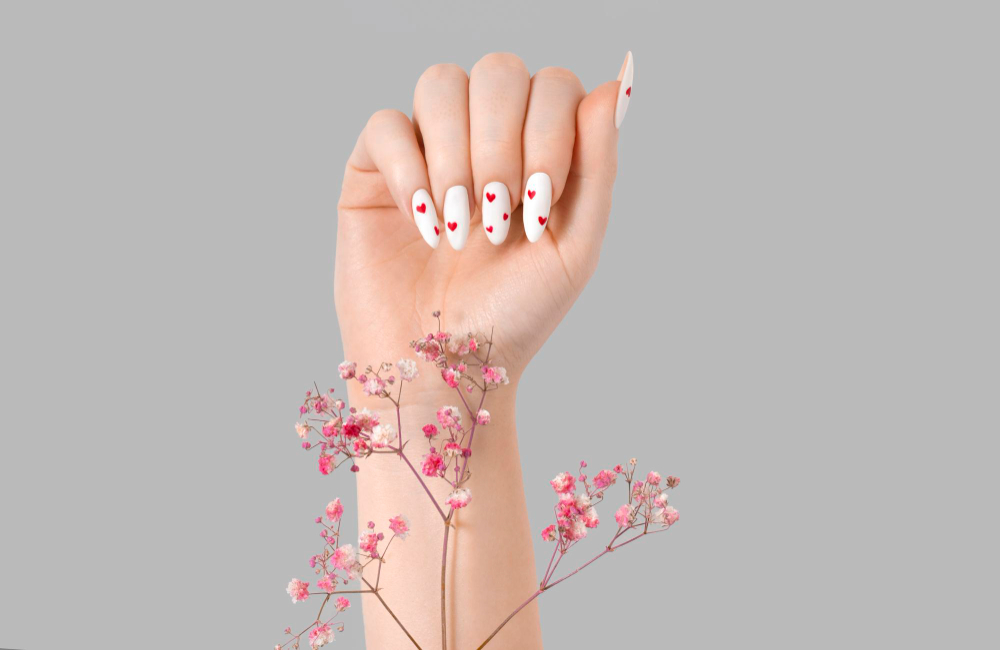manicure-female-hand-with-gypsophila-flowers-gel-polish-white-long-nails-red-hearts-desing